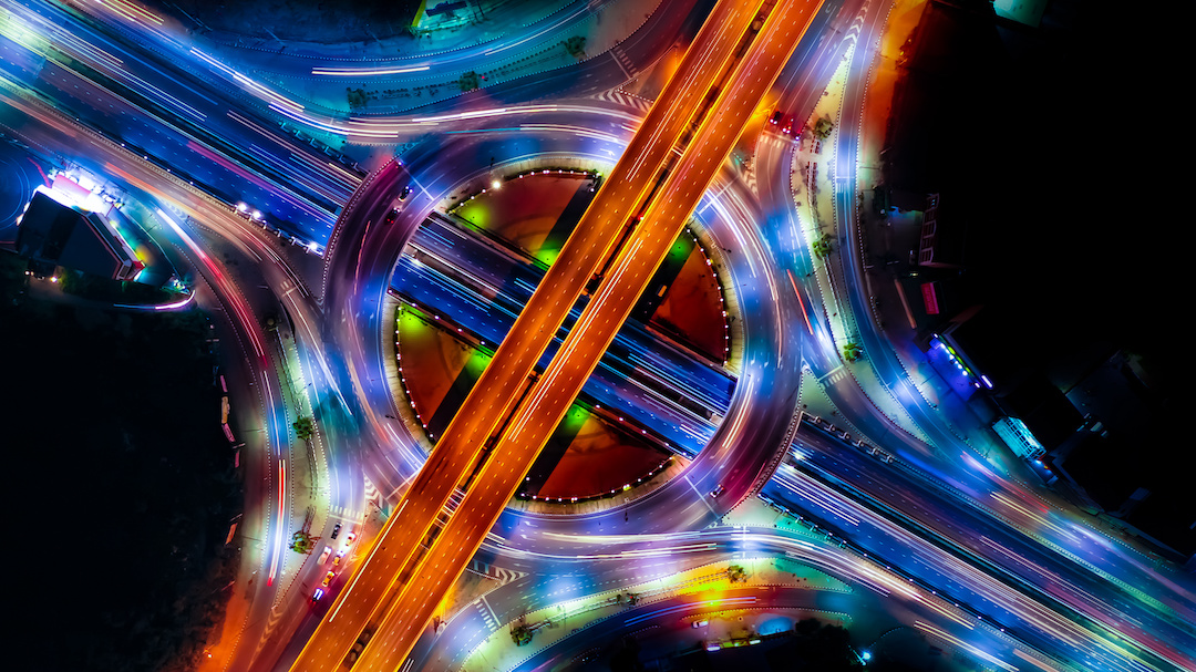 Highway Interchange at night, showing motion of speeding cards, to communicate the idea of faster processes through AI Test Automation by Aquila.